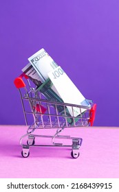 Shopping Trolley Cart With US Dollars And Euro Currency Banknotes Over Trendy Purple Violet Background. Vertical Shot