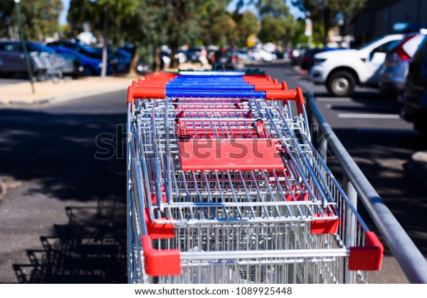 Shopping trolleys in an outdoor car park,\
blurred background.