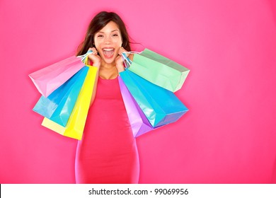 Shopping Woman Happy Excited And Cheerful Holding Shopping Bags Showing Fresh Energetic Smile On Pink Background. Beautiful Smiling Happy Multiracial Caucasian / Chinese Asian Brunette Fashion Model.