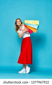 Shopping woman with packages Red skirt sneakers t shirt blue background                                - Shutterstock ID 1377967922