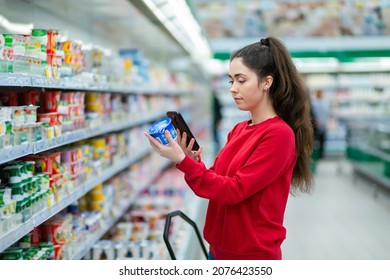 Shopping. A young pretty woman scans the qr code on a product using cellphone. Indoor. Concept of modern technologies and shopping. - Shutterstock ID 2076423550