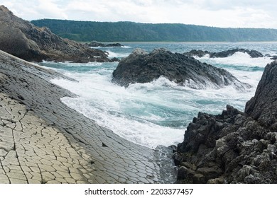shore in natural lava causeway, sea surf among coastal rocks overlooking the distant shore - Shutterstock ID 2203377457