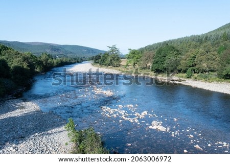 Shore of River Dee in Ballater in Aberdeenshire in Scotland. It is an important area for wildlife. Forest in the background.