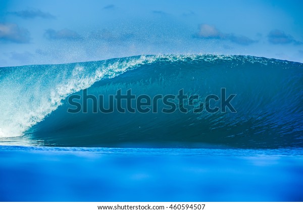 Shorebreak Big ocean wave\
in daylight. Beautiful sky with clouds. Sea Water surface for\
surfing sport front view . Nobody on picture. Vibrant bright\
tropical colorful\
image.