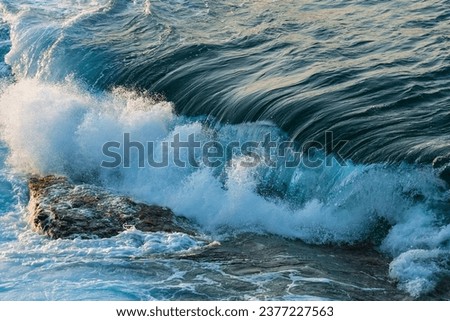 Shorebreak wave hitting a rock in Ikaria with magical colorful sunset lights