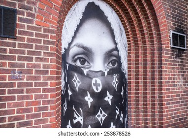 Shoreditch, London, UK, January 11 2015: Street art in London: portrait of a muslim woman wearing burka with Louis Vuitton symbols on it. It refers to the contrast between islamic and western culture.