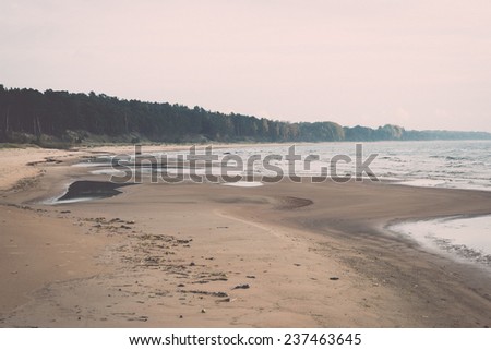 Shoreline of Baltic sea beach with rocks and sand dunes under clouds - retro, vintage style look