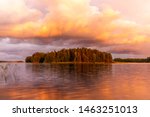 The shores of the calm Saimaa lake in Finland under a nordic sky on fire with a rainbow