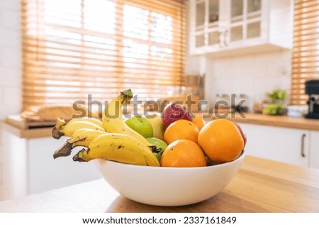 Short of Basket and fresh fruits on wooden table in kitchen at home. Mix variety of fresh juicy colorful healthy fruits in basket on dining counter in house.