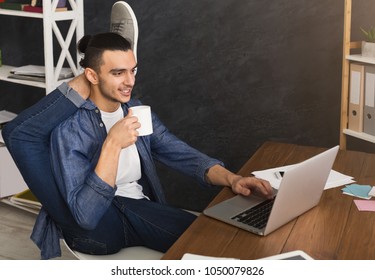 Short break for yoga in office. Flexible man practicing yoga at workplace, while typing on laptop and having coffee, copy space. Active employee at work, healthy lifestyle concept - Shutterstock ID 1050079826