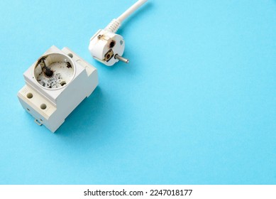 Short circuit, burnt plug of an electrical household appliance and a din socket with traces of burning. Fire hazard due to incorrect use of electrical appliances