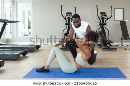 Short curly black hair coach with moustache and beard teach young woman in sportswear the right way to sit-up. Cardio machines are on the background at the gym. Stok fotoğraf © 