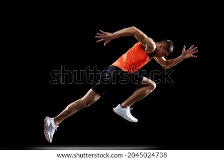 Short distance running. Male professional athlete in uniform training running isolated over black studio background. Maintaining health and strength. Concept of sport, healthy lifestyle, motion, ad