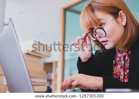 Short eye-sighted woman looking at laptop computer up close. She has a problem with her eye as she become a middle aged person. This portrait photo is suitable for glasses theme.