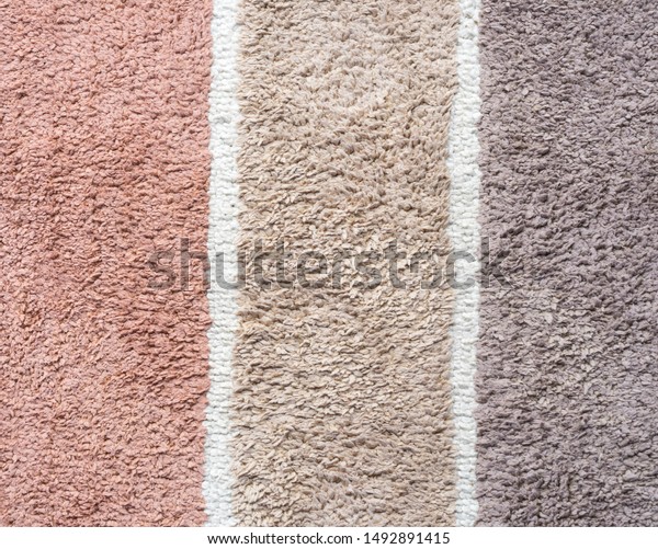 Short hair weaving carpet, vertical or column\
stripe of earth tone, pink, dark beige and brown, divided by white\
line. Soft touch fabric. For home living accessory and cloth\
pattern texture\
background