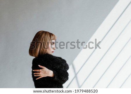 Short hair woman in a black fluffy sweater hugging herself