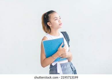 A short haired student wearing a white sleeveless top and printed skirt holding her school notes looking away. isolated on a white background - Shutterstock ID 2195713199