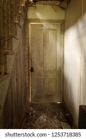 Short Hallway Leading To A Closed Door In An Abandoned House. Natural Light.                               