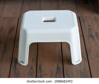 Short Legs White Plastic Chair, Square Head, 4 Legs, On Wooden Floor, Can See Top Of Chair, Close Up