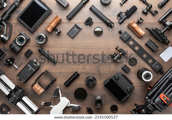 Short movie production essentials on wooden\
background with copy space in center. Different video making\
equipment for indie cinema production. Video production tools on\
brown table view from\
above.