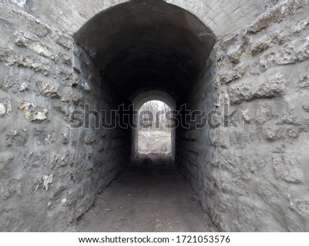 A short old stone tunnel under a railway bridge.          