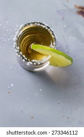 Short Of Tequila Anejo With Lime And Salt Over Gray Metal Table. Overhead View.