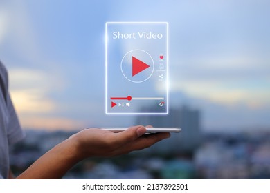 Short Video marketing concept. Man hands holding mobile phone showing virtual short video player with blurred city as background