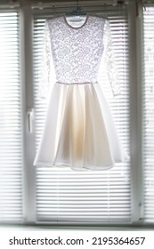 Short Wedding Dress Hanging On The Window.