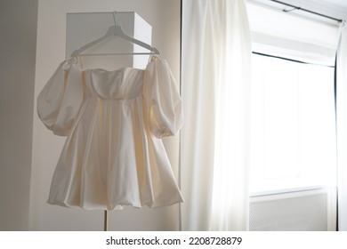 Short Wedding Dress. Wedding Dress Hanging On A Floor Lamp