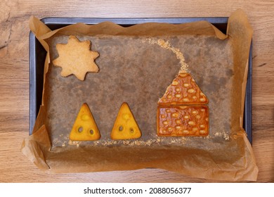 Shortbread cookies placed in order to form a house in baking tin on a wooden table.