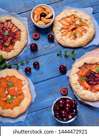 Shortbread galette pies with apricots, cherries and apples topped with mint on the blue wooden table