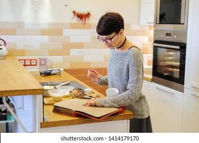 Short-haired woman to cook chocolate fondant recipe from cookbook. The girl preparing to bake a sweet dessert in the kitchen. - Powered by Shutterstock