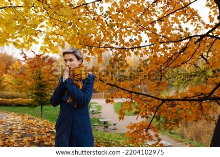 Similar – Image, Stock Photo Short-haired woman warms her hands with her breath in the autumn in the park