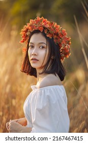 A Short-haired Woman Wears A Maple Leaf Crown In A Meadow.