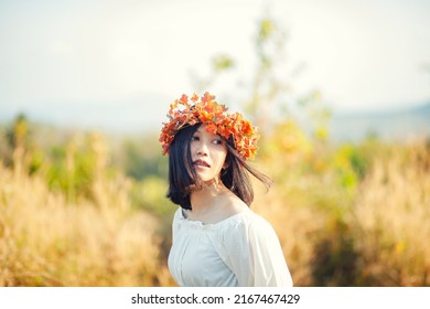 A Short-haired Woman Wears A Maple Leaf Crown In A Meadow.