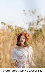 A Short-haired Woman Wears A Maple Leaf Crown In A Meadow.