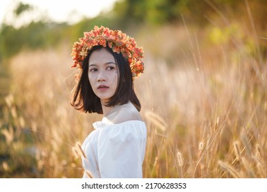 A Short-haired Woman Wears A Maple Leaf Crown In A Meadow.