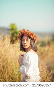 A Short-haired Woman Wears A Maple Leaf Crown In A Meadow.