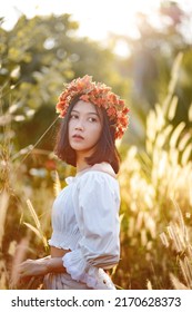 A Short-haired Woman Wears A Maple Leaf Crown In A Meadow.