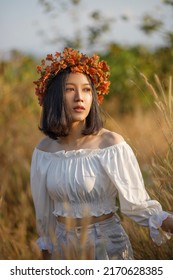 A Short-haired Woman Wears A Maple Leaf Crown In A Meadow.