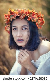 A Short-haired Woman Wears A Maple Leaf Crown In A Meadow.