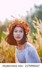 A Short-haired Woman Wears A Maple Leaf Crown In A Meadow.