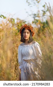 A Short-haired Woman Wears A Maple Leaf Crown In A Meadow.