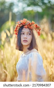 A Short-haired Woman Wears A Maple Leaf Crown In A Meadow.