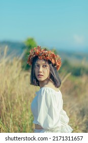 A Short-haired Woman Wears A Maple Leaf Crown In A Meadow.