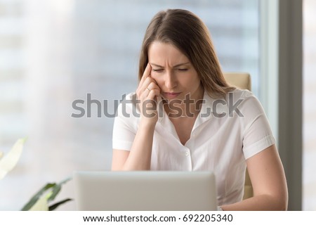 Shortsighted businesswoman squinting eyes looking at pc laptop screen while sitting at home office, tired of computer thoughtful woman having poor weak eyesight, bad sight, blurry vision, need glasses