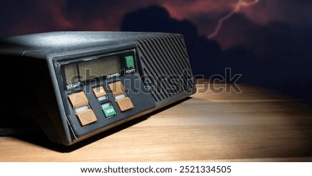 Shortwave transceiver with a lightning strike coming from the clouds behind on a wood table.
