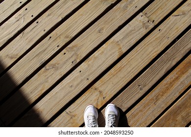 Shot From Above Of A Brownish Wooden Dock With View Of Slippers. Diagonal Lines.