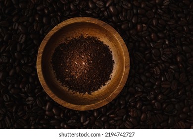 Shot From Above, Ground Coffee Beans In A Small Wooden Bowl. Coffee Beans Surrounding The Object. Monochromatic Brown Food And Drink Theme Photo With Copy Space