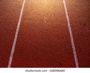 Shot From Above Of A Red Running Track. Strong Sun Shines From Outside The Frame.